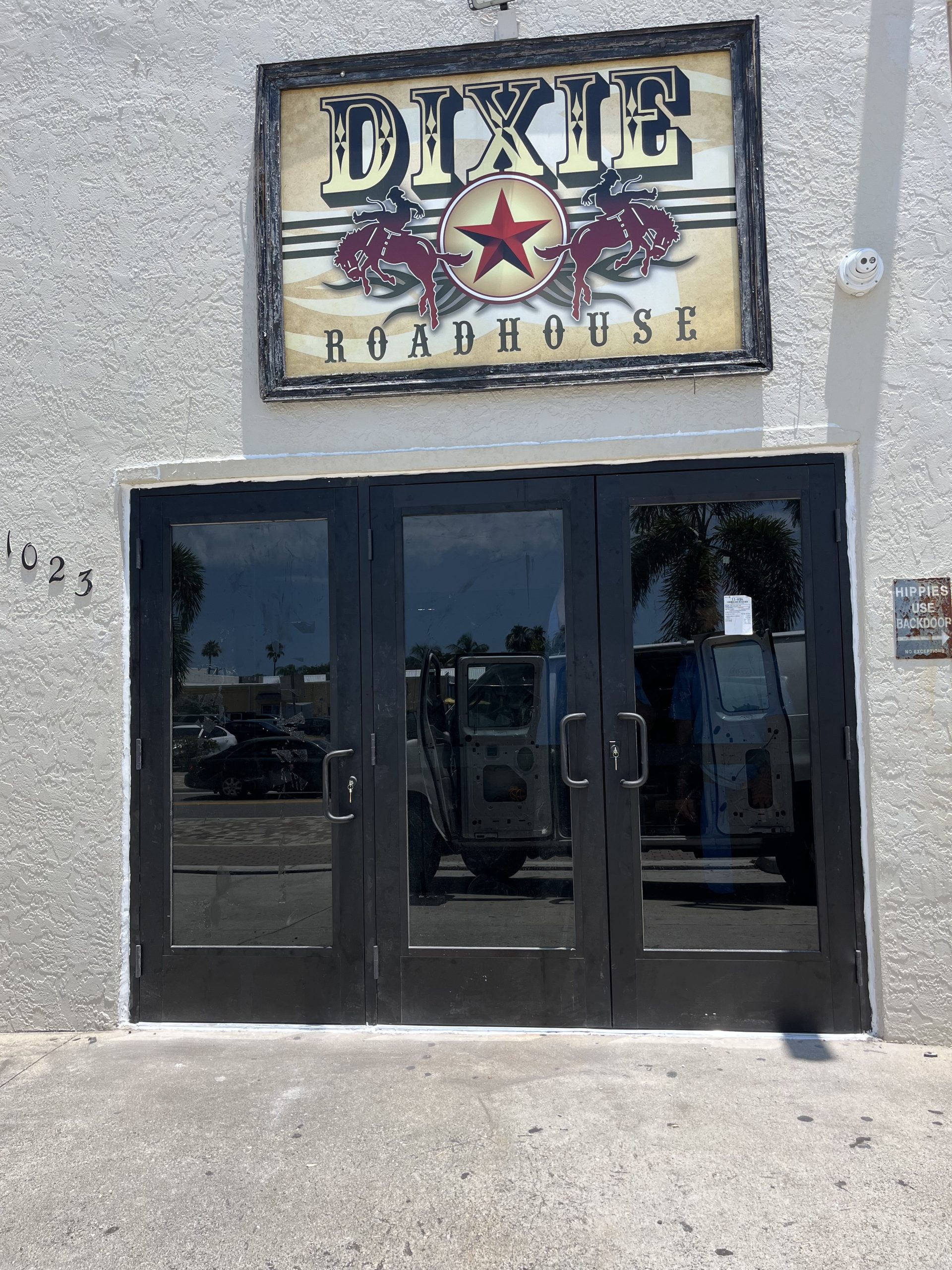 Dixie Roadhouse entrance featuring double glass doors and a prominent sign, reflecting the vibrant atmosphere of a popular dining venue in Southwest Florida.